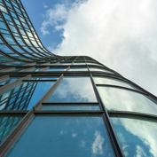 A modern, curved skyscraper rises toward the sky, symbolizing the concept of elevating investments and financial growth.