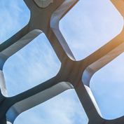 A modern, geometric architectural roof against a bright, sunny sky